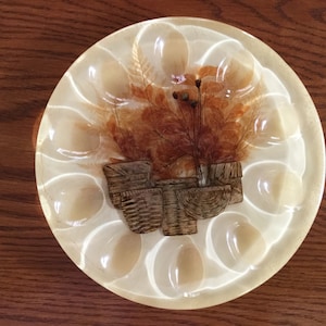 May include: A white egg holder with a brown floral design and a cluster of small brown baskets in the center.