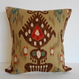 May include: A decorative throw pillow with a brown, red, and white ikat pattern on a beige background.