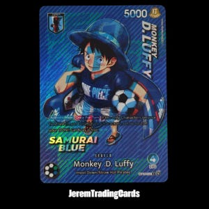 Peut inclure: Une carte à collectionner One Piece holographique représentant Monkey D. Luffy avec un chapeau et un t-shirt bleus, tenant un ballon de football. La carte affiche le texte 5000 Strike, Samurai Blue, Leader Monkey D. Luffy et des règles de jeu.