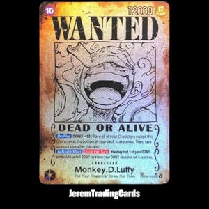 May include: A trading card with a "WANTED" poster design featuring a cartoon character with a large open mouth. The card has text that reads "DEAD OR ALIVE" and "Monkey.D.Luffy". The card has a gold and silver colour scheme.