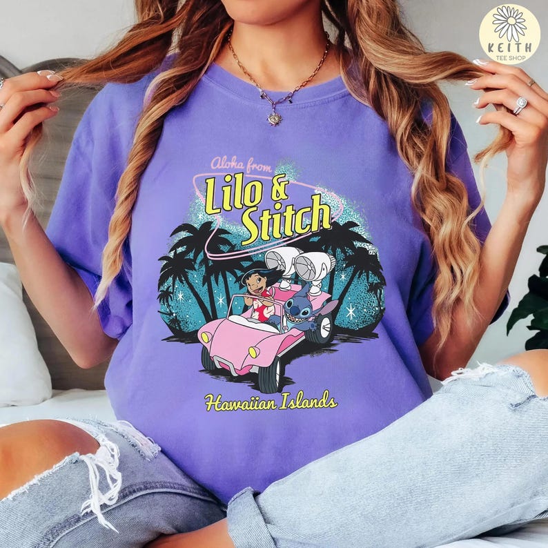 May include: A purple t-shirt featuring a graphic of Lilo and Stitch in a pink car, with the text "Aloha from Lilo & Stitch" and "Hawaiian Islands". The design includes palm trees and a tropical scene.