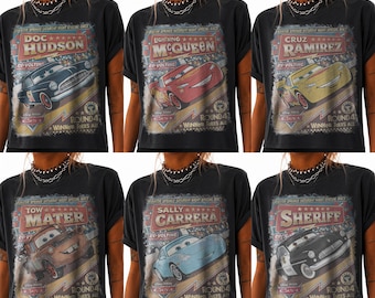 May include: A black t-shirt featuring a vintage-style graphic print of Disney Pixar Cars characters including Doc Hudson, Lightning McQueen, Cruz Ramirez, Tow Mater, Sally Carrera, and Sheriff, with text reading Radiator Springs Saturday Night Special Race.
