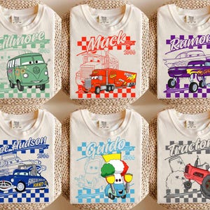 May include: Six off-white t-shirts with cartoon car graphics. Each shirt features a different character: Fillmore, Mack, Ramone, Doc Hudson, Guido, and Tractors. The designs include the character's name and the year 2006, set against a checkered background.