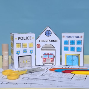 Könnte beinhalten: Ein Bastelprojekt für Kinder mit Papiermodellen eines Polizeireviers, einer Feuerwache und eines Krankenhauses. Die Gebäude sind weiß mit farbigen Details und Text. Ein Klebestift, eine Schere und Buntstifte sind ebenfalls vorhanden.