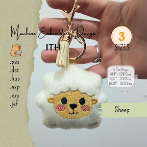 May include: A white plush sheep keychain with a gold-tone metal clasp and a cream-colored tassel. The sheep face is embroidered with yellow, black, and pink thread. Text includes Machine Embroidery Design, ITH, 3 SIZES, Sheep, and file formats .pes, .dst, .hus, .exp, .xxx, .jef, plus dimensions 4x4, 5x7, and 6x10 inches.