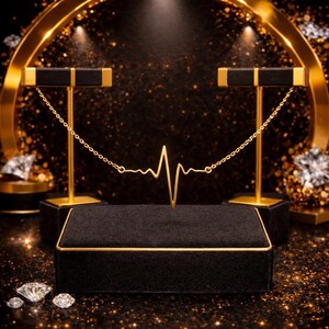 Peut inclure: Un collier en or en forme de battement de c&oelig;ur est pr&eacute;sent&eacute; sur un pr&eacute;sentoir &agrave; bijoux en velours noir avec des bordures dor&eacute;es. Deux supports dor&eacute;s avec des dessus noirs soutiennent la cha&icirc;ne du collier. Des diamants sont dispers&eacute;s.