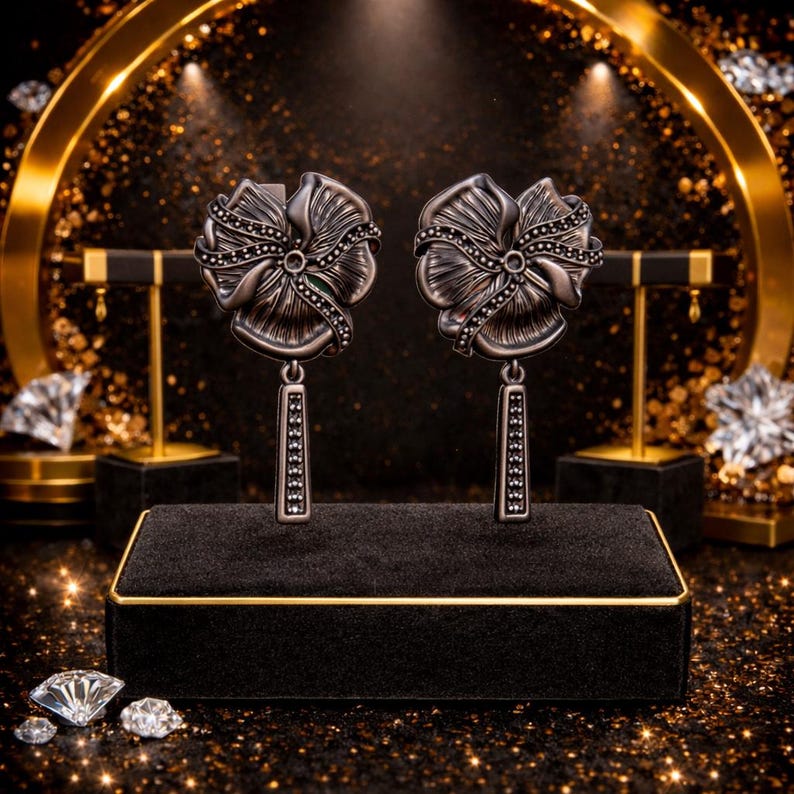 Peut inclure: Une paire de boucles d'oreilles argent&eacute;es en forme de fleur avec des accents de pierres noires. Chaque boucle d'oreille pr&eacute;sente un motif floral d&eacute;taill&eacute; avec un &eacute;l&eacute;ment rectangulaire pendant. Les boucles d'oreilles sont expos&eacute;es sur un pr&eacute;sentoir &agrave; bijoux en velours noir.