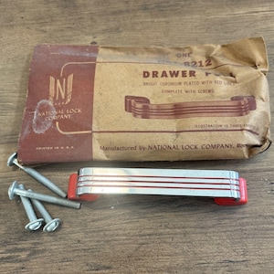 May include: A vintage drawer pull with bright chrome plating and red accents, along with several screws. The packaging reads "DRAWER PULL" and "NATIONAL LOCK COMPANY". The drawer pull is approximately 6 inches long.