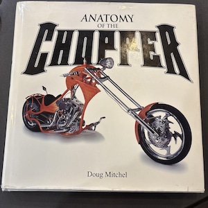 May include: A book titled "Anatomy of the Chopper" featuring an orange custom motorcycle on the cover. The book's title is in bold, black, stylized lettering. The author's name, Doug Mitchel, is printed below the title.