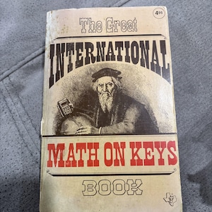 May include: Vintage book titled "The Great International Math on Keys Book." The cover features an illustration of a bearded man holding a globe and a calculator. The book has a worn, aged appearance with a price tag in the upper right corner.
