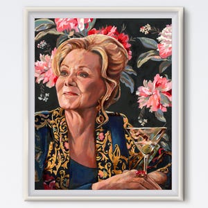 May include: A framed portrait of a woman with blonde hair, wearing a blue and gold patterned jacket, holding a martini. The background features a dark floral pattern with pink and red flowers.