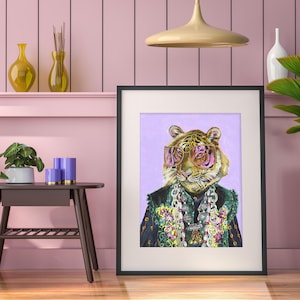 May include: A framed print of a tiger wearing pink sunglasses and a colorful beaded necklace. The tiger is depicted against a light purple background.