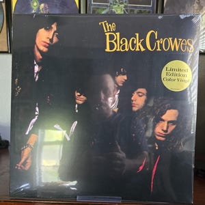 May include: Sealed vinyl record album by The Black Crowes. The album cover features a group of men in dark clothing against a black background. The text "The Black Crowes" is in yellow. A sticker reads "Limited Edition Color Vinyl."