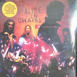 Könnte beinhalten: Alice in Chains Unplugged Schallplattencover mit roter und oranger Bühnenbeleuchtung. Das Cover zeigt die Bandmitglieder, das MTV Unplugged-Logo und einen gelben runden Aufkleber mit den Songtiteln: Would?, Rooster, Over Now, A Killer Is Me.