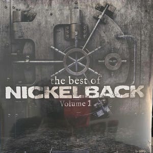 Op de afbeelding: Een vierkante vinyl hoes met een metalen kluisdeurontwerp in grijze en zwarte tinten. De tekst "the best of NICKELBACK Volume 1" staat in witte letters in het midden, geplaatst over de afbeelding van de industriële kluisdeur.