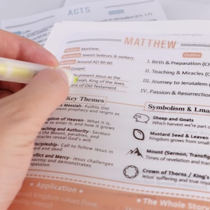 Könnte beinhalten: Eine Hand, die einen gelben Textmarker über einem offenen Buch hält. Das Buch ist auf einer Seite mit dem Titel "Matthäus" geöffnet, mit Text über das Evangelium und wichtige Themen. Weitere Seiten sind im Hintergrund sichtbar.