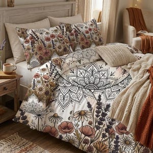 May include: A bed with floral bedding, including a duvet cover and pillowcases. The duvet features a large black and white mandala design and floral borders. The pillowcases and duvet border have a floral pattern with pink, brown, and white flowers. A beige throw blanket and rug complete the cozy bedroom.