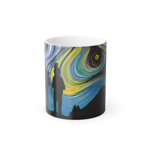 Puede incluir: Taza de cerámica blanca con un diseño de remolino colorido en tonos azules, amarillos y verdes, que recuerda a un cielo estrellado. Siluetas de personas de pie sobre una cordillera oscura.