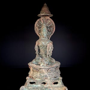 Könnte beinhalten: Eine detaillierte Bronzestatue einer sitzenden Figur mit einem ruhigen Ausdruck. Die Figur ist mit komplizierten Details geschmückt, darunter ein Heiligenschein und ein kunstvoller Kopfschmuck. Die Statue ist auf einem dekorativen Sockel montiert.