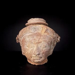 Puede incluir: Una taza de cerámica blanca con un asa negra y el texto "But First, Coffee" en negrita negra. La taza está llena de un líquido oscuro, probablemente café, y se encuentra sobre una superficie de color claro.