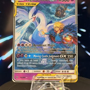 K&ouml;nnte beinhalten: Eine Pok&eacute;mon-Sammelkarte mit Lugia & Howl GX. Die Karte hat eine farbenfrohe Illustration einer wei&szlig;en und blauen Fabelwesen und einer Figur mit blonden Haaren. Die Karte enth&auml;lt den Text "Aeroblast Magic" und "Moving Castle Judgment GX 250".