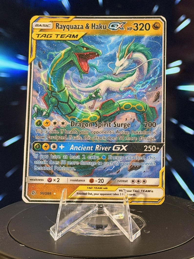 K&ouml;nnte beinhalten: Eine Rayquaza & Haku GX Tag Team Sammelkarte. Die Karte zeigt eine gr&uuml;ne und wei&szlig;e Drachenillustration mit dem Text "Dragon Spirit Surge" und "Ancient River GX". Die Karte wird auf einem transparenten Kunststoffst&auml;nder pr&auml;sentiert.