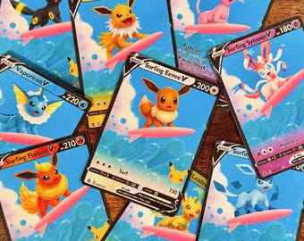 Könnte beinhalten: Eine Sammlung farbenfroher Sammelkarten mit verschiedenen Zeichentrickfiguren, die auf rosa Surfbrettern vor blauem Ozeanhintergrund surfen. Die Karten haben unterschiedliche Namen und Punktwerte, wobei einige Karten mit "Surfing Eevee V" und "Surfing Sylveon V" beschriftet sind.