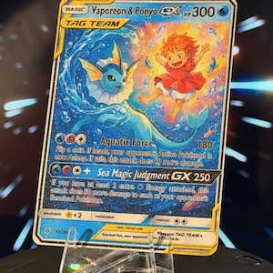 K&ouml;nnte beinhalten: Eine Pok&eacute;mon-Sammelkarte mit Vaporeon und Ponyo. Die Karte hat ein blaues und goldenes Farbschema mit dem Text "Vaporeon & Ponyo GX HP300". Die Karte wird auf einem transparenten Acrylst&auml;nder pr&auml;sentiert.