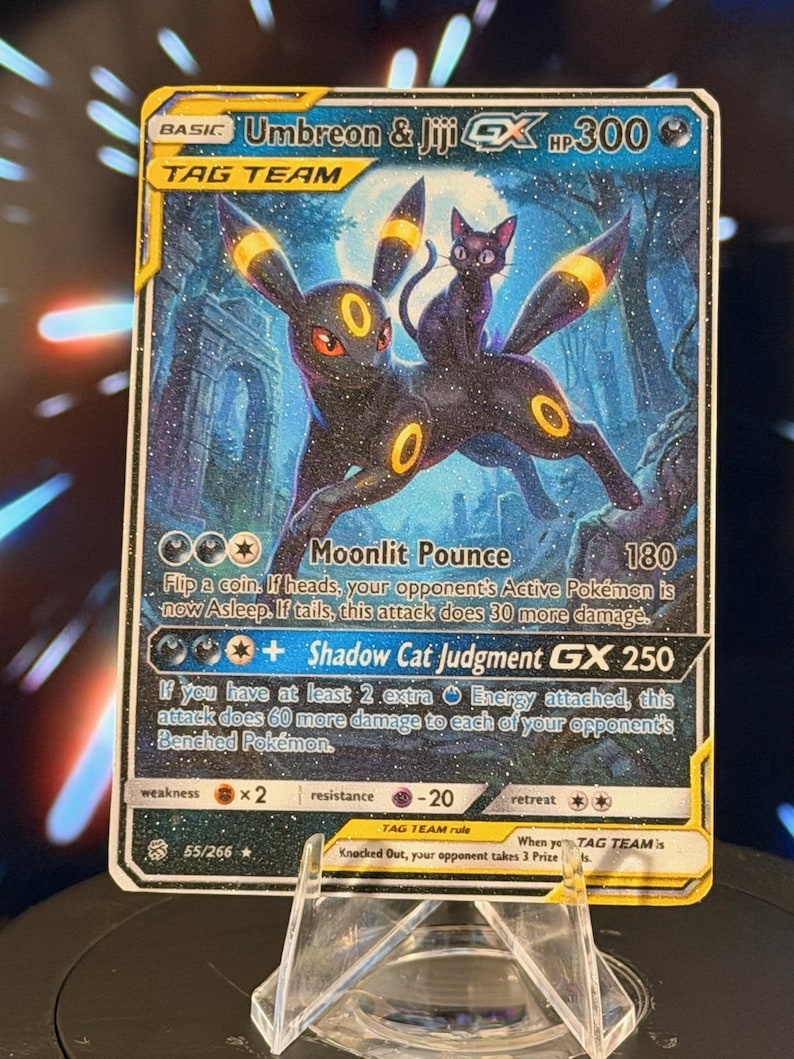 K&ouml;nnte beinhalten: Eine Pok&eacute;mon-Sammelkarte mit Umbreon und Jiji GX. Die Karte hat einen dunkelblauen Hintergrund mit den beiden Charakteren im Vordergrund. Die Karte enth&auml;lt Text, der die F&auml;higkeiten und Werte des Charakters beschreibt. Die Karte wird in einem transparenten Kunststoffhalter angezeigt.