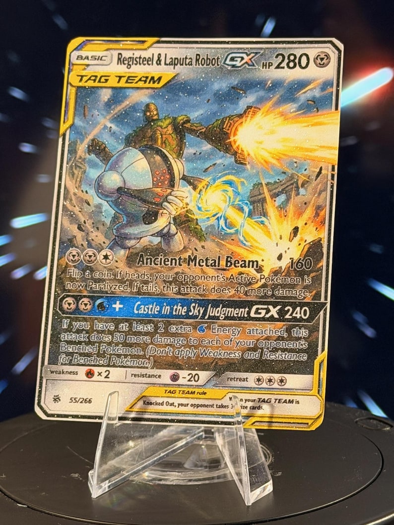 K&ouml;nnte beinhalten: Eine Pok&eacute;mon-Sammelkarte mit Registeel & Laputa Robot GX. Die Karte zeigt eine futuristische Kampfszene mit zwei Robotern und den Texten "Ancient Metal Beam" und "Castle in the Sky Judgment GX". Die Karte wird auf einem transparenten Kunststoffst&auml;nder pr&auml;sentiert.