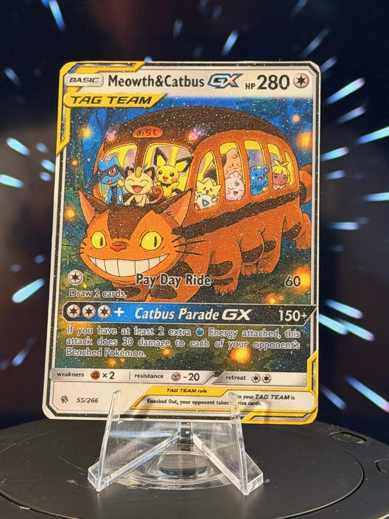K&ouml;nnte beinhalten: Eine Sammelkarte mit einem Cartoon-Katzenbus und verschiedenen Cartoon-Charakteren. Die Karte tr&auml;gt die Aufschrift "Meowth&Catbus GX" und "Catbus Parade GX". Die Karte wird auf einem transparenten Kunststoffst&auml;nder pr&auml;sentiert.