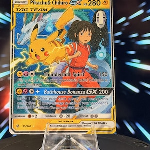 K&ouml;nnte beinhalten: Eine Pok&eacute;mon-Sammelkarte mit Pikachu und Chihiro aus Spirited Away. Die Karte hat ein gelbes und blaues Design mit dem Text "Pikachu & Chihiro GX HP 280". Die Karte wird auf einem transparenten Kunststoffst&auml;nder pr&auml;sentiert.