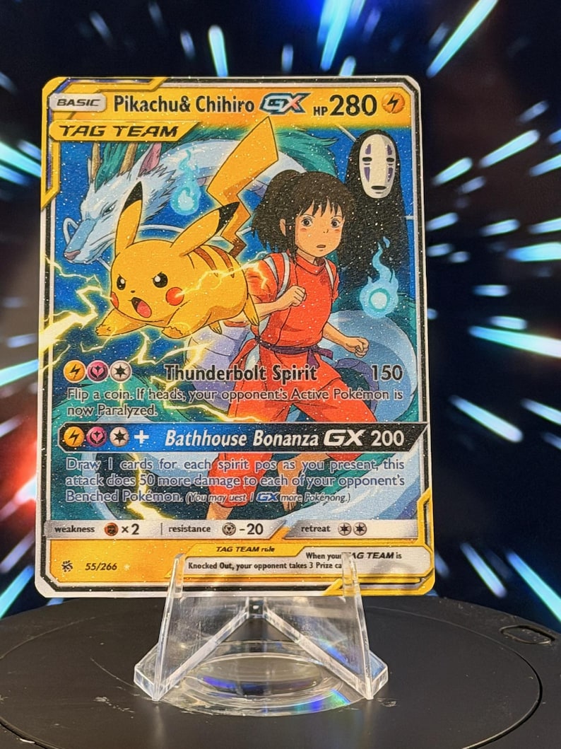 K&ouml;nnte beinhalten: Eine Pok&eacute;mon-Sammelkarte mit Pikachu und Chihiro aus Spirited Away. Die Karte hat ein gelbes und blaues Design mit dem Text "Pikachu & Chihiro GX HP 280". Die Karte wird auf einem transparenten Kunststoffst&auml;nder pr&auml;sentiert.
