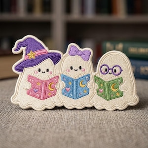 May include: An embroidered patch featuring three cream-colored ghosts reading books. The left ghost wears a purple witch hat, the middle ghost has a purple bow, and the right ghost wears purple glasses. Each ghost holds a colorful book with moon and star motifs.