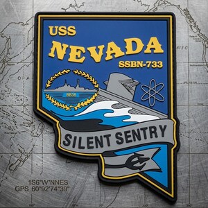 May include: A rectangular patch with a blue background features the text "USS NEVADA SSBN-733" in yellow. Below, a gray submarine design and the words "SILENT SENTRY" are displayed. The patch includes a gold emblem and a trident symbol.