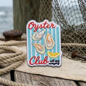 May include: An embroidered patch featuring a light blue and white vertical striped background with three oysters and a yellow lemon wedge. The red text reads Oyster Club, and the black text reads all day everyday in a cursive script font.