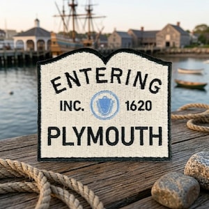 May include: A rectangular embroidered patch with a cream-colored background and a black border. The text reads ENTERING, INC. 1620, and PLYMOUTH in black, with a small blue circular emblem featuring a shell icon centered between the text.