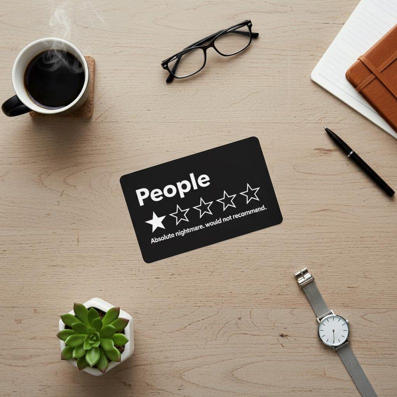 Puede incluir: Una pegatina rectangular negra con la palabra "People" en blanco, una calificaci&oacute;n de una estrella y el texto "Absolute nightmare, would not recommend." Sobre una superficie de madera, con una taza de caf&eacute;, gafas y un reloj.
