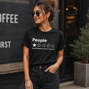Puede incluir: Camiseta negra con la palabra "People" encima de una calificaci&oacute;n de una estrella y la frase "Absolute nightmare, would not recommend." La camiseta la lleva una persona con gafas de sol y vaqueros oscuros.