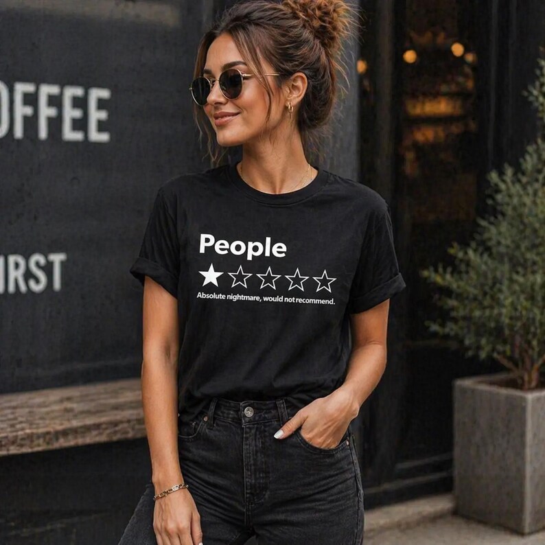 Puede incluir: Camiseta negra con la palabra "People" encima de una calificaci&oacute;n de una estrella y la frase "Absolute nightmare, would not recommend." La camiseta la lleva una persona con gafas de sol y vaqueros oscuros.