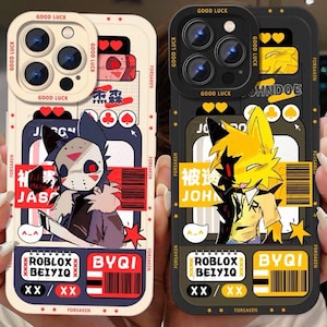 以下が含まれることがあります： ユニークなデザインの携帯電話ケース2つ。1つはオフホワイトで漫画のキャラクターとテキスト、もう1つは黒で黄色のキャラクターです。両方のケースには「GOOD LUCK」、「FORSAKEN」、「ROBLOX BEIYIQ」、「BYQI」の文字が入っています。