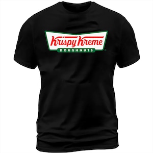 May include: Black t-shirt featuring the Krispy Kreme logo. The logo is a white, red, and green design with the words "Krispy Kreme" in red script and "DOUGHNUTS" in green block letters. The shirt is a classic crew neck.