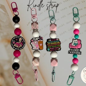 May include: Four Kindle straps featuring colorful silicone beads and metal clasps. Each strap includes a unique charm: a skeleton reading, an iced coffee and books graphic, a text-based book lover design, and a cat reading in a pink chair.