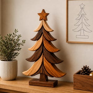 May include: A decorative wooden Christmas tree sculpture composed of stacked, curved segments in varying shades of brown wood, topped with a five-pointed star. The tree stands on a rectangular wooden base, featuring a smooth, polished finish.
