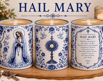 May include: Three white ceramic mugs with blue handles and blue floral patterns. The first mug features an illustration of the Virgin Mary, the second a monstrance, and the third the text of the Hail Mary prayer. Each mug contains a coffee beverage.