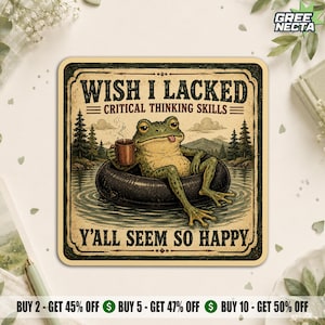 May include: A square coaster featuring a green frog floating in a black inner tube on a lake, holding a brown mug. The text reads WISH I LACKED CRITICAL THINKING SKILLS Y'ALL SEEM SO HAPPY. The design includes pine trees and mountains.