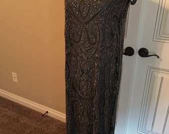 May include: A long, sleeveless, black sequined dress with a round neckline and a paisley pattern.