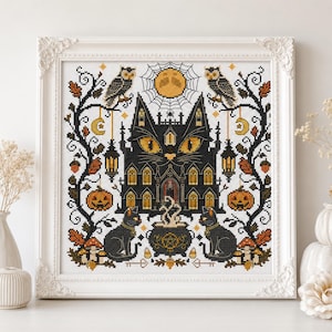 K&ouml;nnte beinhalten: Ein gerahmtes Kreuzstichbild mit einem schwarzen, katzenf&ouml;rmigen Spukhaus mit leuchtend gelben Augen. Das Design umfasst Eulen, K&uuml;rbisse, einen Kessel und einen Vollmond, alles im Halloween-Thema. Das Kunstwerk ist in einem wei&szlig;en, verzierten Rahmen gerahmt.