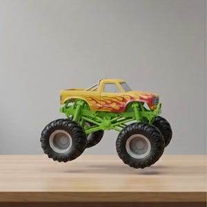 May include: A yellow and red monster truck toy with large black tires and green suspension. The truck features flame decals on the side and is designed for off-road play. A fun toy for kids.