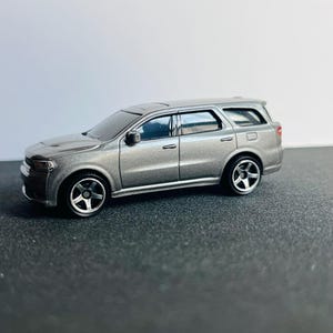 以下が含まれることがあります： 黒いホイールが付いたシルバーのSUVのダイキャストモデル。 ミニチュアカーは、サンルーフと色付きの窓を含む詳細なデザインです。 おもちゃの車はダッジデュランゴのレプリカです。